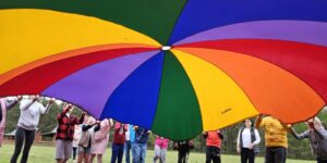 Zdjęcie przedstawia uczestników pikniku podczas zabawy chustą
